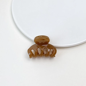 Close-up of a small brown jelly hair claw clip with a glossy finish on white surface