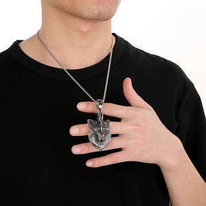 Macro shot of a punk style stainless steel wolf head pendant on a male model wearing black