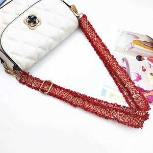Detail of red frayed woven shoulder strap with gold buckle on white quilted handbag