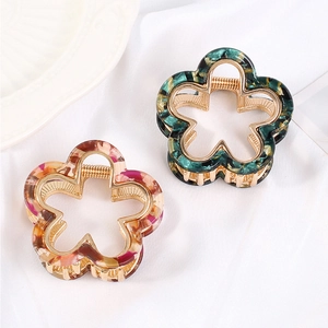 Close-up of floral acetate hair claws in green and pink marble with gold metal accents