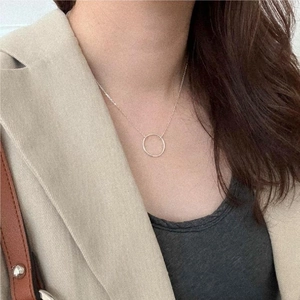 Close-up of a minimalist S925 sterling silver geometric circle pendant on a model's neck