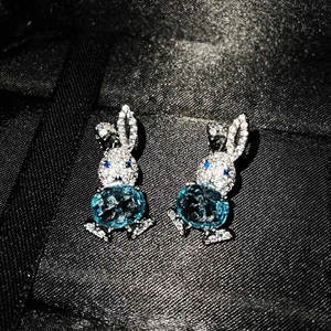 Cute pavé diamond bunny earrings featuring an oval sky blue gemstone on black fabric