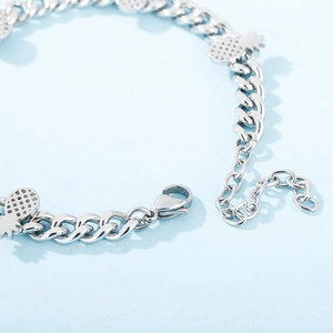 Detail view of silver pineapple charm bracelet with adjustable lobster clasp and metal chain