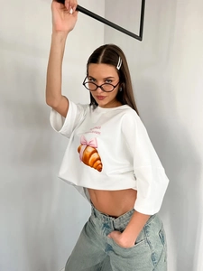 Λεπτομέρεια από λευκό βαμβακερό oversized T-shirt με σχέδιο κρουασάν και ροζ φιόγκο