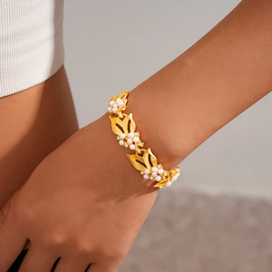Dettaglio della collana a foglia d'oro regolabile con perle sul polso della modella