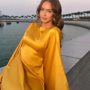 Elegant yellow satin maxi dress with batwing sleeves in a sunny outdoor beach setting