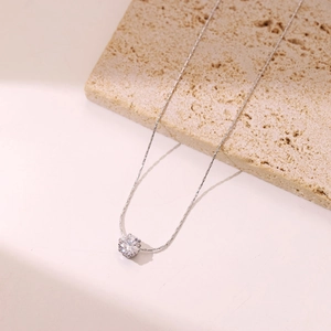 Elegant silver necklace with round sparkling diamond pendant on stone surface