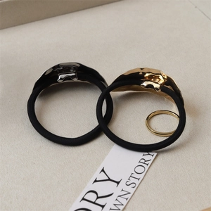 Close-up of irregular gold and silver textured alloy hair ties with black elastic bands