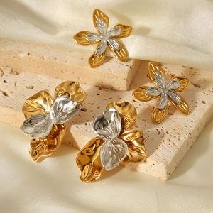Detailed macro view of two-tone hammer textured flower earrings on elegant stone and silk