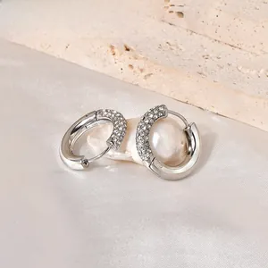 Detail of silver hoop earrings with micro-pave cubic zirconia on an elegant pearl