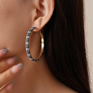 Close-up of model wearing gold-toned round hoop earrings with black and white houndstooth fabric