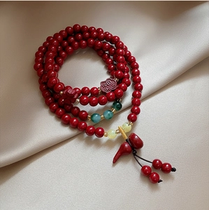 Detail of red beaded bracelet with Fu character charm on elegant silk background