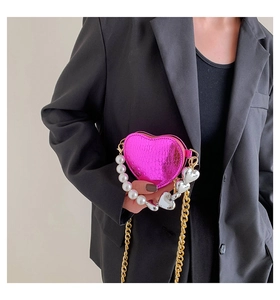 Détail du mini-sac rose en forme de cœur avec poignée en perles et texture serpent