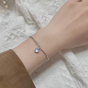 Detail of a chic double-layered silver heart bracelet with a blue moonstone on a wrist