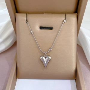 Silver heart pendant necklace on snake chain displayed in a gold gift box on white silk