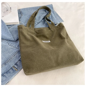 Flat lay of army green canvas tote bag with FASHION label on white fabric background
