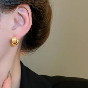 Close-up of golden interlocking rings earring with brushed and polished metal textures