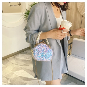 Close-up of white sequins seashell bag with pearl handle and golden chain on a model