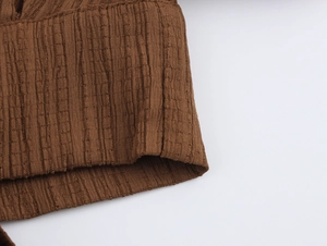 Detailed macro view of dark brown smocked fabric texture with vertical ribbed patterns