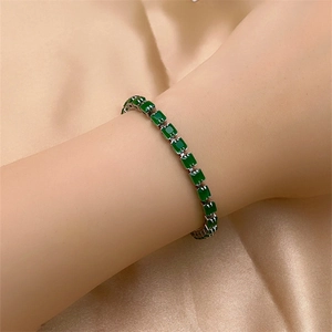 Elegant silver bracelet with square green zircons on champagne silk background