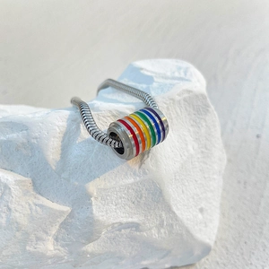 Close-up of rainbow cylindrical bead on polished steel snake chain against stone