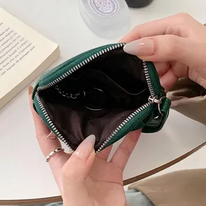 Mini portamonete in pelle verde con cerniera e portachiavi in un contesto elegante