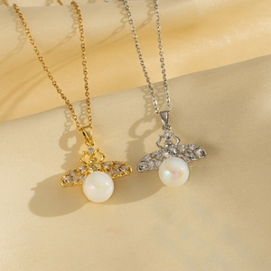 Minimalist gold and silver bee pearl necklaces with gemstone wings on silk background