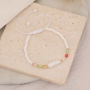 Close-up of handmade beaded bracelet with irregular pearl on a textured stone surface