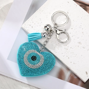 Macro detail of heart-shaped evil eye keychain with blue rhinestones and tassel
