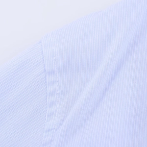 Detail view of light blue striped shirt fabric texture and shoulder stitching craftsmanship