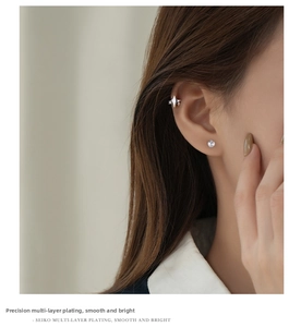 Macro detail of s925 silver star ear cuff and round zircon stud on model ear