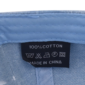 Detail of internal care label on washed denim cap showing 100% cotton fabric and stitching