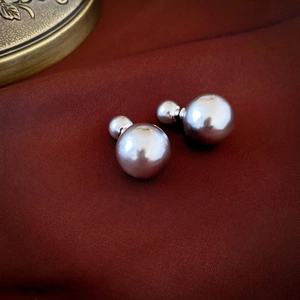 Macro view of vintage silver-grey double pearl earrings on dark velvet background