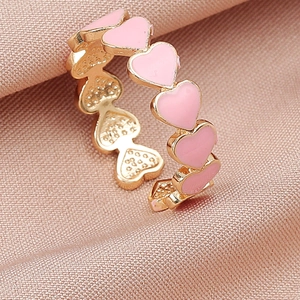 Dettaglio dell'anello a forma di cuore con smalto rosa su seta rosa delicata