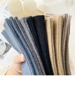 Macro detail of thick knitted fingerless gloves with vertical ribbed texture in various colors