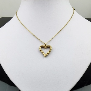 Détail du collier pendentif cœur doré avec texture martelée présenté sur un buste blanc