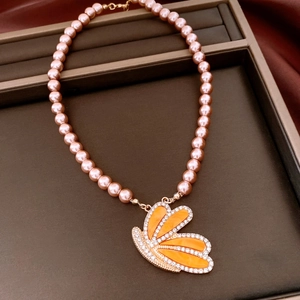 Close-up of pink pearl necklace with orange butterfly pendant in a velvet jewelry box