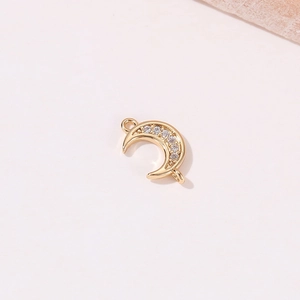 Macro shot of a golden crescent moon pendant with micro-set zircons for DIY jewelry
