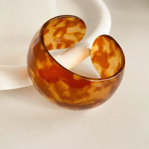 Macro detail of tortoiseshell pattern resin bangle with a chunky C-shaped open design