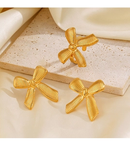 Detailed view of 18K gold-plated bow jewelry with textured surface on silk fabric