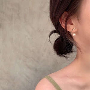 Close-up of elegant gold tassel earrings with pearls and crystals on a female model