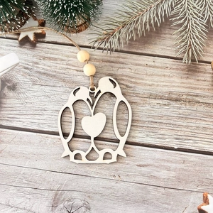 Detail view of penguin wood ornament with heart element and twine on pine branch