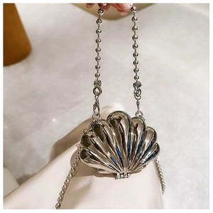 Detailed view of a silver shell-shaped mini evening bag with a beaded chain handle