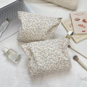 Close-up of two floral corduroy makeup bags with gold zipper and branded woven label