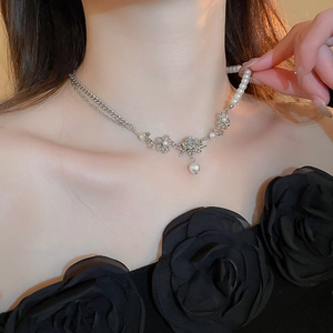 Elegant metallic rose flower necklace with pearls on a model wearing a black dress