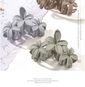 Detail of three matte flower hair claws in morandi colors with secure grip design