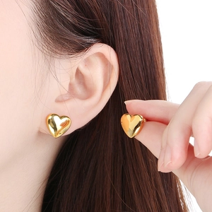 Detail of gold heart earrings on model showing size and elegant metal finish