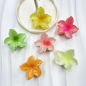 Set of six colorful gradient plumeria flower hair claws on a textured white surface