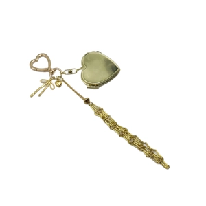 Golden heart locket keychain with bow charm and long metal tassels on white background