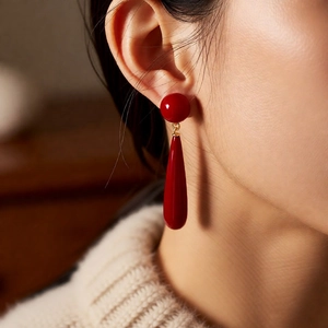 Close-up of elegant red teardrop pearl earrings hanging on female model's ear